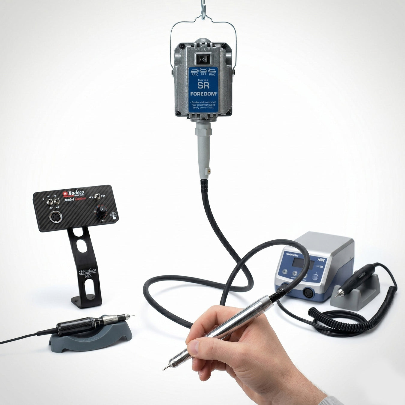 Jeweler's hand gripping a Foredom flex shaft handpiece with NSK and Badeco rotary micromotor systems